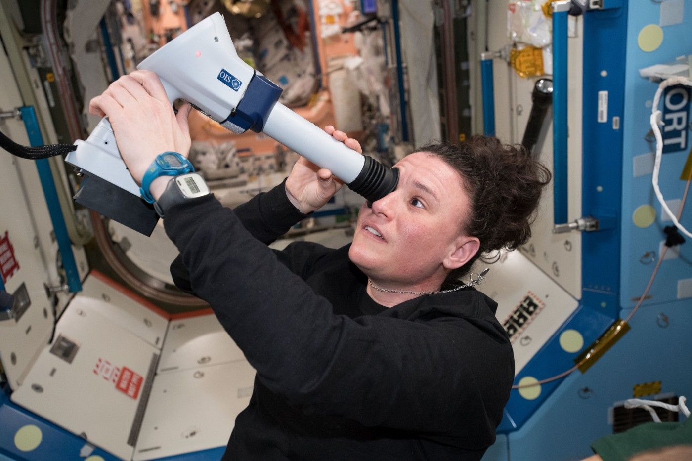 A photo from NASA’s tweet about Dr. Auñón-Chancellor on the International Space Station, where a young woman looks through a telescopic instrument.